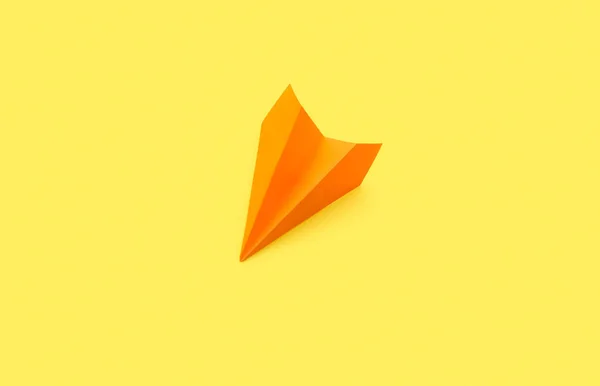 Orange paper plane on yellow background