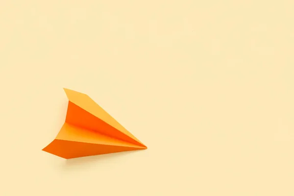 Orange paper plane on beige background