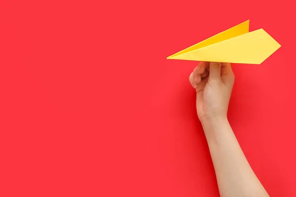 Woman with yellow paper plane on red background