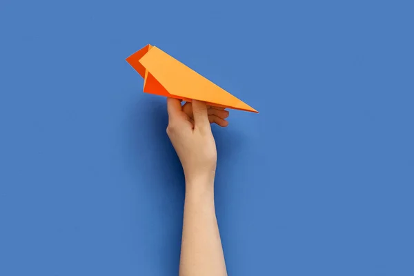 Woman with orange paper plane on blue background