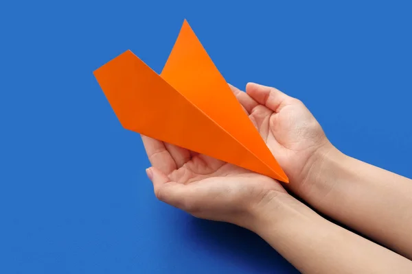 Woman with orange paper plane on blue background