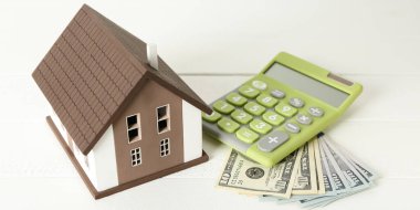 House model, calculator and money on white table. Concept of buying new property
