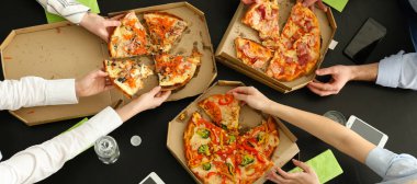 Young people eating tasty pizza at table in office, top view