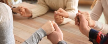 Group of people praying together at table, closeup