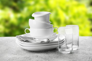 Set of clean dishes with cutlery and glasses on grunge table outdoors