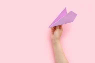 Woman with lilac paper plane on pink background