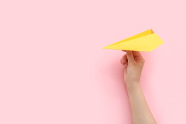 Woman with yellow paper plane on pink background