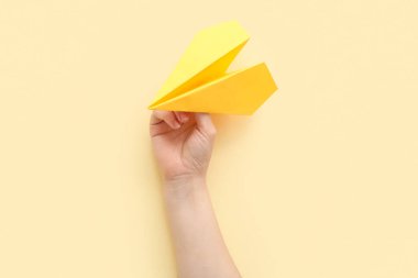 Yellow paper plane on beige background