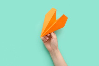 Woman with orange paper plane on color background