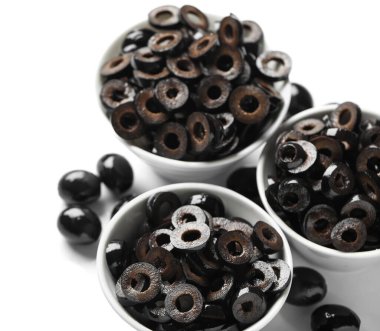 Bowls of cut black olives on white background, closeup