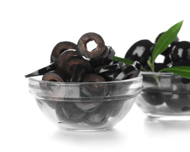 Glass bowls of cut black olives on white background, closeup