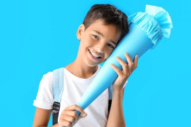 Little boy with school cone on blue background