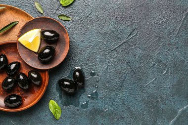 Composition with plates of tasty black olives on dark color background