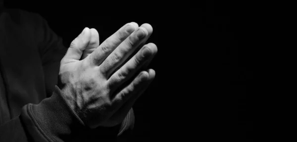 Hands of religious man praying on dark background, closeup