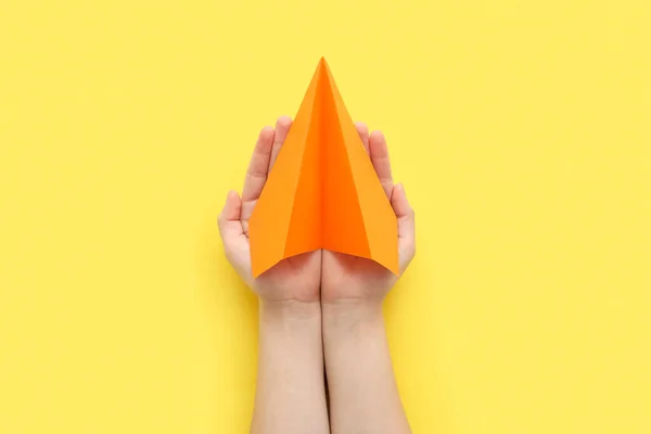 Woman with orange paper plane on yellow background