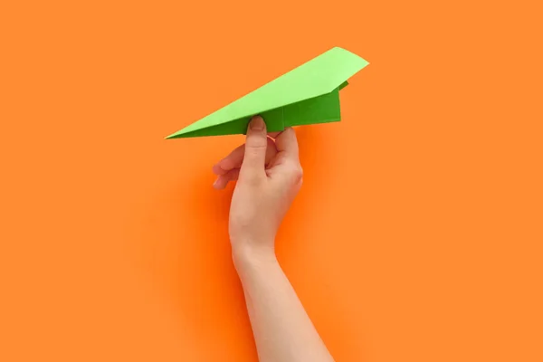 Woman with green paper plane on orange background