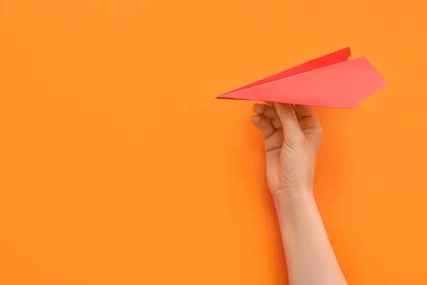 Woman with red paper plane on orange background