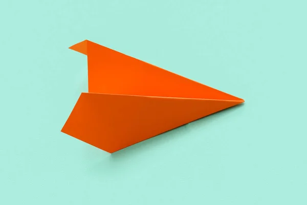 Orange paper plane on color background