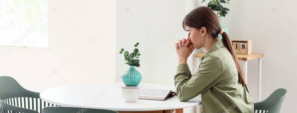 Young woman with Bible praying at home