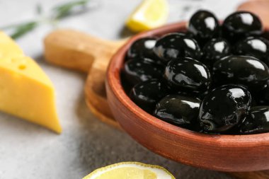 Plate of tasty black olives on table, closeup