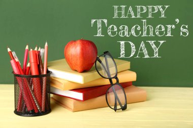 School stationery, glasses and apple on table in classroom. Happy Teacher's Day