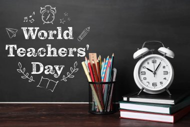 School stationery, books and alarm clock on table in classroom. World Teacher's Day