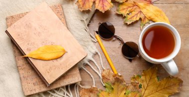 Autumn composition with books, cup of aromatic tea and sunglasses on wooden background