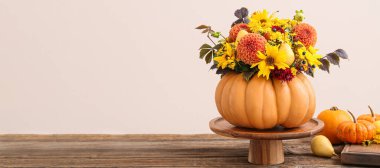 Beautiful autumn bouquet in pumpkin on table against light background. Banner for design