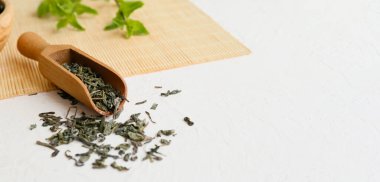 Scoop with dry tea leaves on table