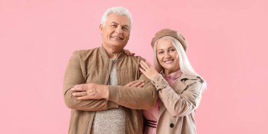 Portrait of stylish elderly couple on pink background