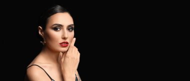 Pretty young woman with beautiful makeup on dark background with space for text