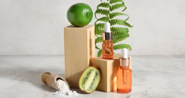 Bottles of natural cosmetics and ingredients on light background with space for text