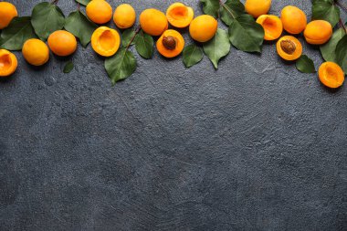 Composition with ripe apricots and green leaves on dark color background