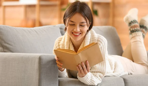 Evdeki Kanepede Kitap Okuyan Mutlu Genç Bir Kadın — Stok fotoğraf