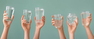 Female hands with glasses of water on green background