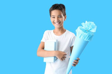 Little boy with school cone and books on blue background