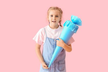 Cute little girl with blue school cone on pink background