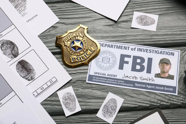 Finger prints with document of FBI agent and badge on wooden background