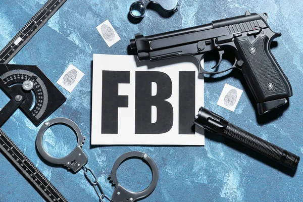 Paper sheet with abbreviation FBI and accessories of agent on color background