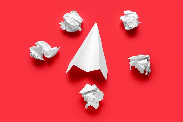 Crumpled paper and plane on red background