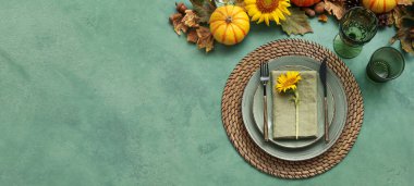Beautiful table setting with autumn decor on green background with space for text