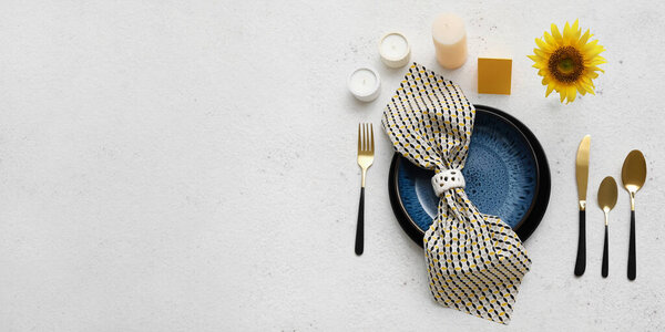 Beautiful table setting with fresh sunflower and aroma candles on light background with space for text
