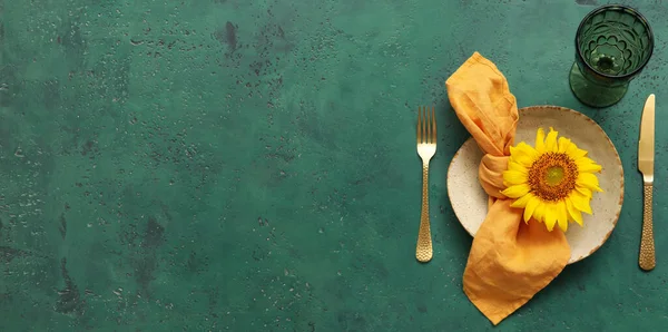 Beautiful table setting with fresh sunflower on green background with space for text