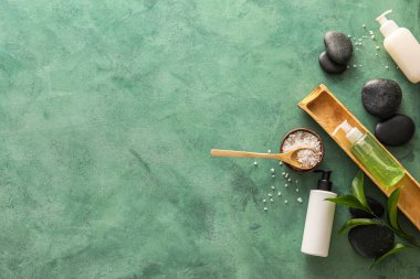 Composition with bottles of cosmetic products, sea salt and spa stones on color background