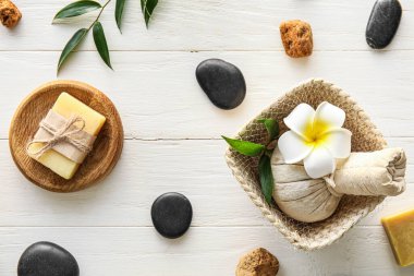 Spa composition with massage bag on light wooden background