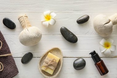 Spa composition with massage bags and tropical flowers on light wooden background