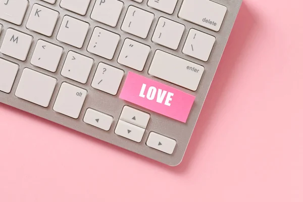 Computer keyboard with text LOVE on pink background. Online dating concept