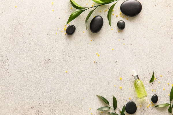 Composition with bottle of essential oil, spa stones and plant branches on light background