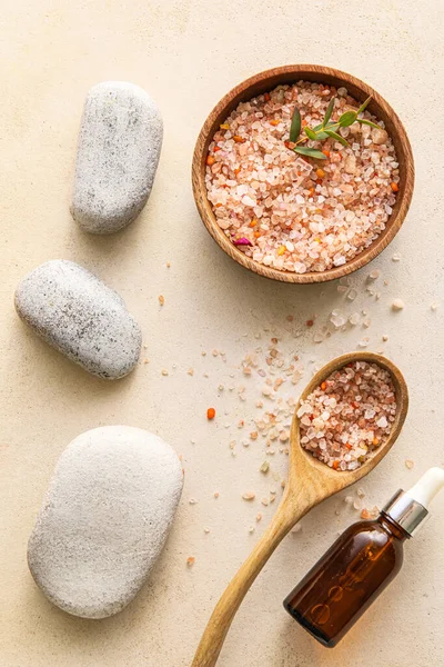 Bowl with sea salt, bottle of essential oil and spa stones on light background