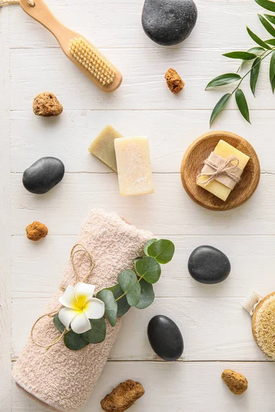 Spa composition with soap bars on light wooden background